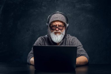 Kulaklıklı, dizüstü bilgisayarda yazan havalı yaşlı adam.