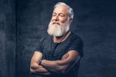 Karanlık arka planda kollarını kavuşturmuş neşeli yaşlı bir adam.