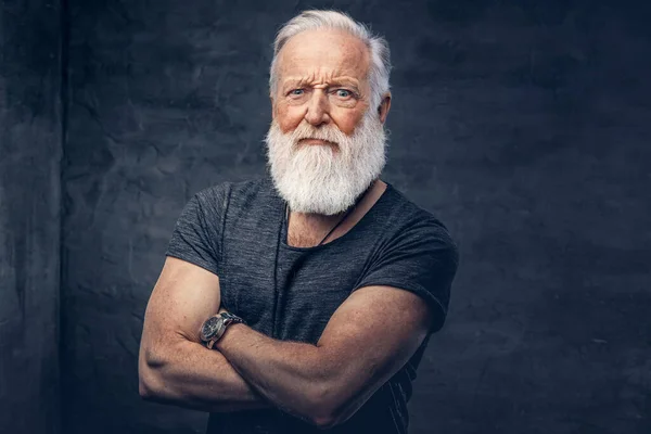 Angry elderly man with crossed arms against dark background — Stok fotoğraf