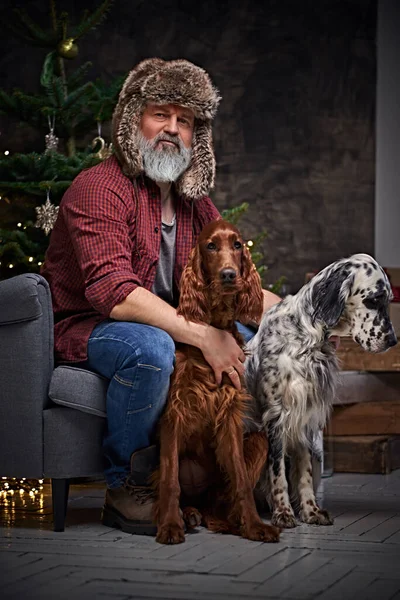 Aged canine pets owner sitting on armchair around christmas tree — Stock Photo, Image