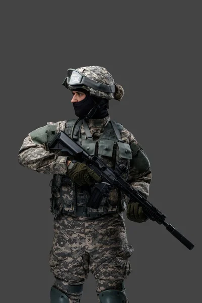 Солдат спецназу з рушницею позує на сірому фоні — стокове фото
