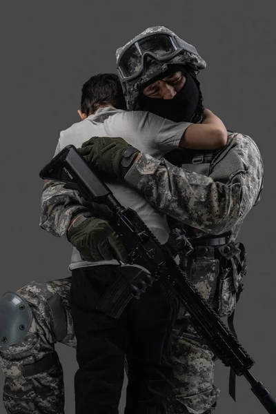 Esercito uomo abbracciando bambino isolato su sfondo grigio — Foto Stock
