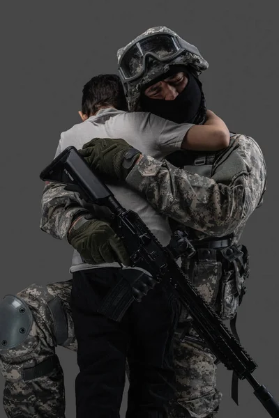 Army man embracing little kid isolated on gray background — Fotografia de Stock