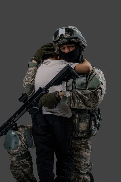 Στρατιώτης που αγκαλιάζει ένα μικρό παιδί απομονωμένο σε γκρι φόντο — Φωτογραφία Αρχείου