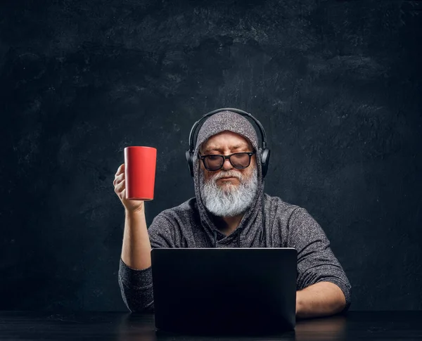 Çağdaş yaşlı bilgisayar korsanı masada oturuyor.