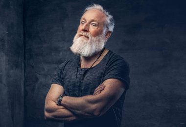 Karanlık arka planda çapraz kolları olan neşeli yaşlı bir adam.