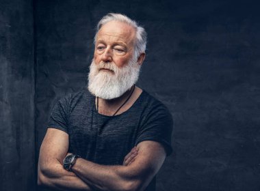 Koyu arkaplanda çapraz kollu kendinden emin yaşlı bir adam.