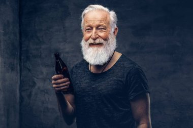 Şişeli neşeli yaşlı adam karanlık arka planda poz veriyor.