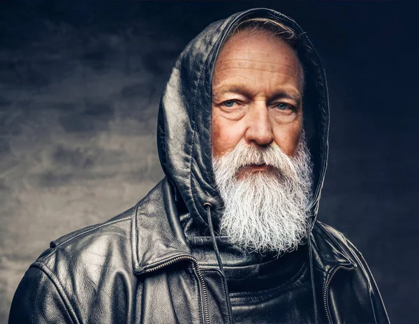 Elderly man dressed in leather jacket with hood against dark background — Photo
