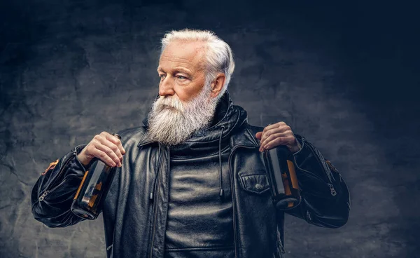 Elderly man biker holding two bottles against dark background — Zdjęcie stockowe