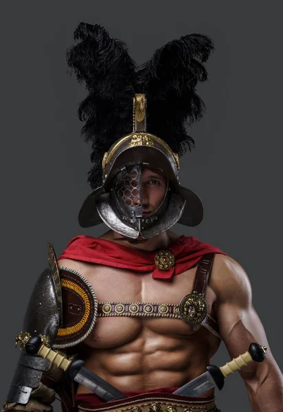 Muscular roman gladiator looking at camera against grey background — Stock Photo, Image