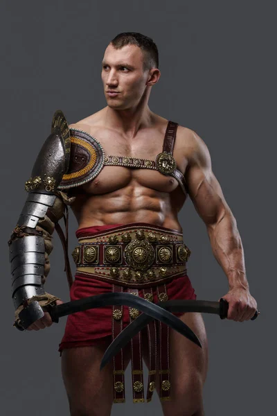 Roman gladiator dual wielding swords against grey background — Stock Photo, Image