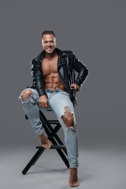 Sandalyeye oturan kaslı, neşeli adam.