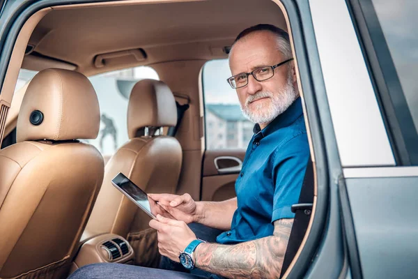 Velho empresário com tablet usando tablet dentro do carro — Fotografia de Stock