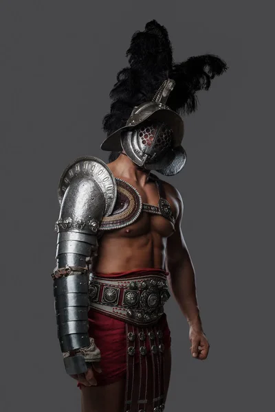 Silny rzymski gladiator ubrany w jasną zbroję i śliwkowy kask — Zdjęcie stockowe