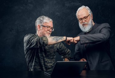 Yaşlı bir adam iş arkadaşını karanlık arka planda yumrukluyor.