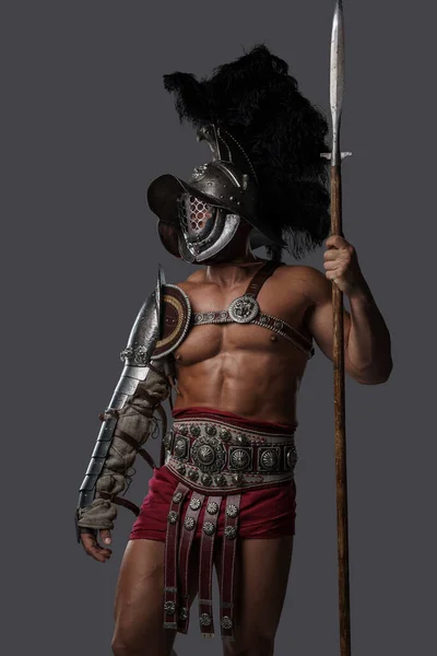 Славный гладиатор-копьеносец со шлемом на сером фоне — стоковое фото