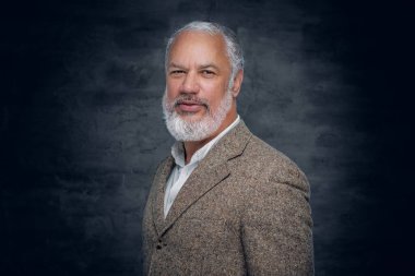 Bej takım elbiseli şık son sınıf öğrencisi kameraya bakıyor.