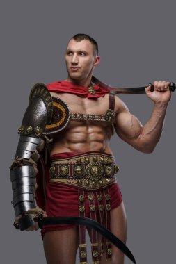 Romalı gladyatör gri arkaplana karşı iki kılıç kullanıyor