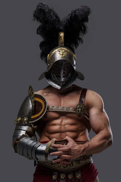 Stark antik gladiator med pluggad hjälm mot grå bakgrund — Stockfoto