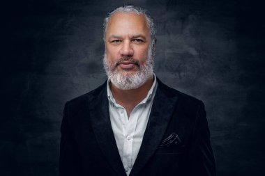 Siyah smokin giymiş yaşlı bir adam karanlık arka planda.