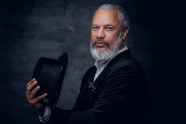 Siyah arka plana karşı şapkalı zarif yaşlı adam.