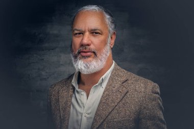 Esmer arka planda bej takım elbiseli zarif yaşlı adam.