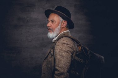 Siyah arka planda şapka ve sırt çantalı son sınıf öğrencisi.