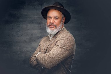 Siyah arka plana karşı şapkası olan kendinden emin kıdemli bir adam.