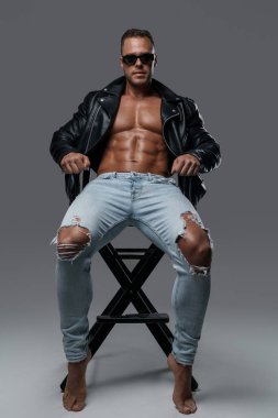 Strong and stylish man sitting on chair against grey background