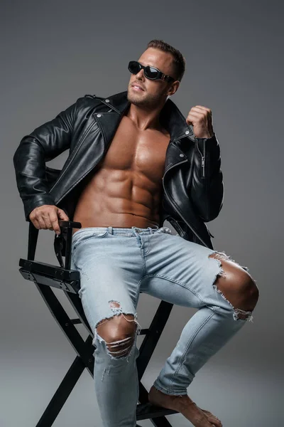 Stylish muscular guy dressed in jeans and leather jacket — Stock fotografie
