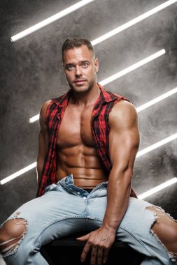 Yırtık pırtık giyinmiş kaslı bir adam.