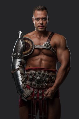 Muscular gladiator with naked torso staring at camera
