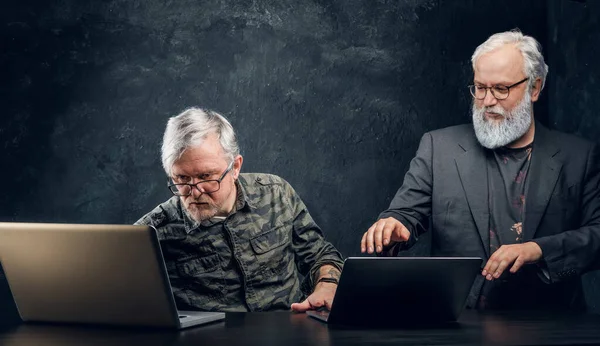 Двоє літніх бізнесменів сидять за столом з ноутбуком — стокове фото