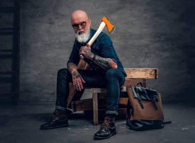 Baltalı yaşlı oduncu tahta üzerinde oturuyor.