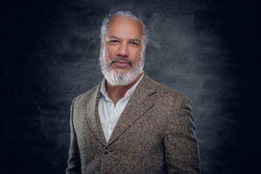 Bej takım elbiseli şık son sınıf öğrencisi kameraya bakıyor.