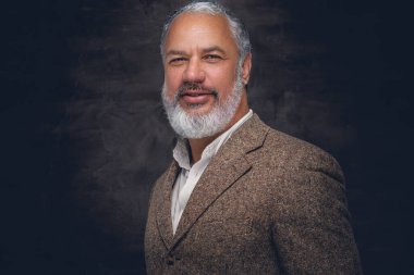 Bej takım elbiseli şık son sınıf öğrencisi kameraya bakıyor.