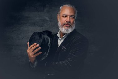 Siyah arka plana karşı şapkalı zarif yaşlı adam.