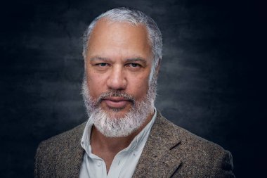 Esmer arka planda bej takım elbiseli zarif yaşlı adam.