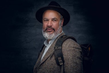 Siyah arka planda şapka ve sırt çantalı son sınıf öğrencisi.