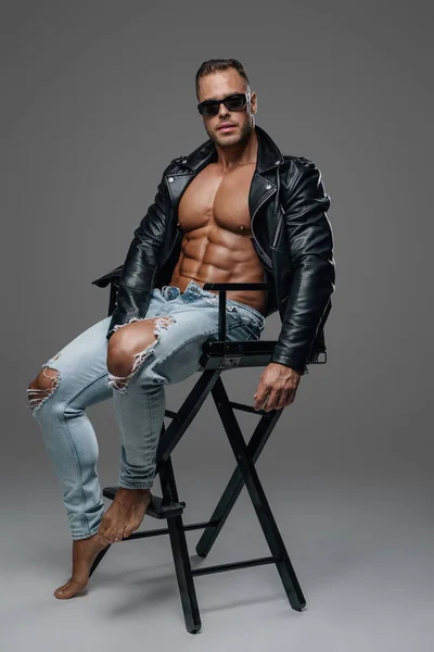 Strong and stylish man sitting on chair against grey background — Stock fotografie