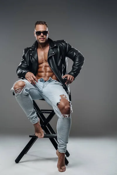 Muscular guy dressed in stylish clothes sitting on chair — Stockfoto