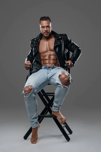 Joyful man with muscular build sitting on chair — стоковое фото