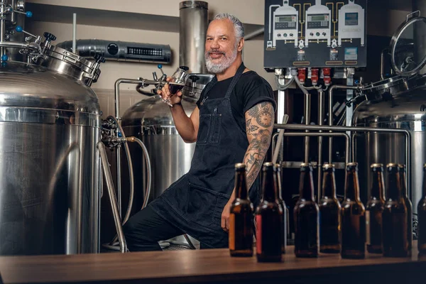 Çelik tankların etrafında bira içen kıdemli bira üreticisi