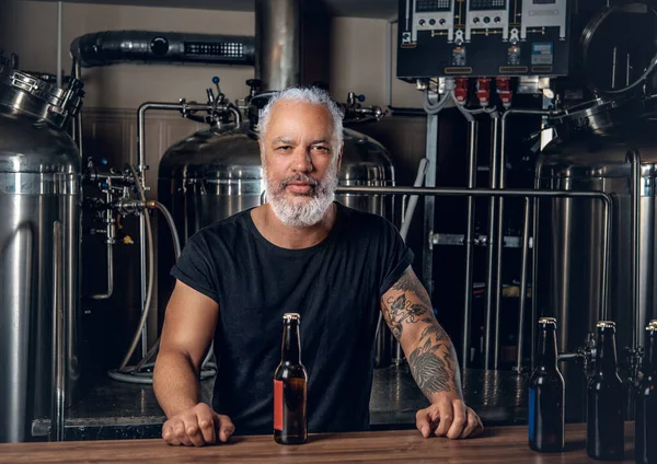 Variller ve bira şişeleri etrafında profesyonel yaşlı bira üreticisi.