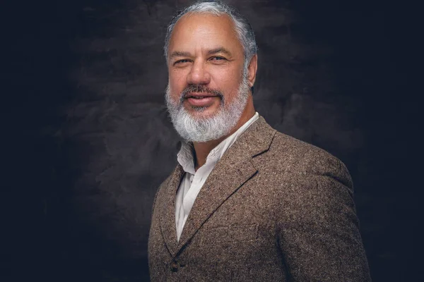 Bej takım elbiseli şık son sınıf öğrencisi kameraya bakıyor.