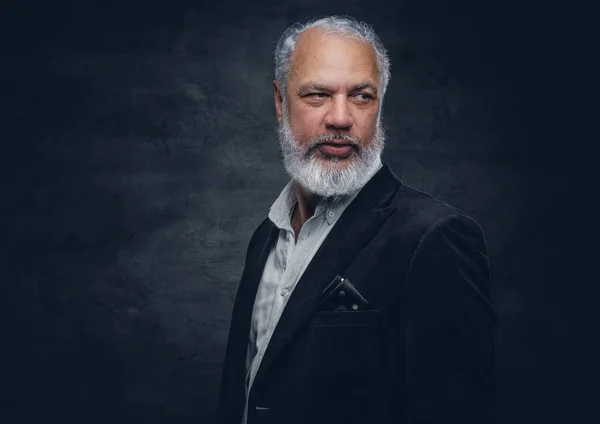 Elderly man dressed in black tuxedo against dark background — Photo