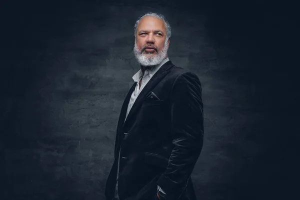 Elderly man dressed in black tuxedo against dark background — Foto Stock