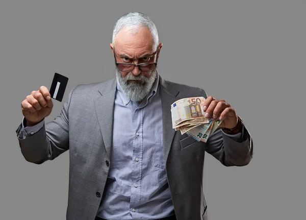 Rich old man with money and bank card against gray background — 스톡 사진
