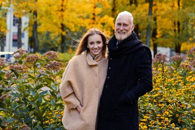 Old man hugging his young daughter outdoors in fall